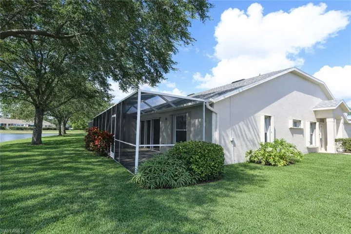 View of property exterior featuring a sunroom, stucco siding, glass enclosure, and a yard