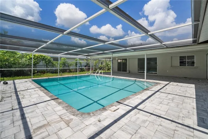 View of swimming pool featuring a patio area and a lanai