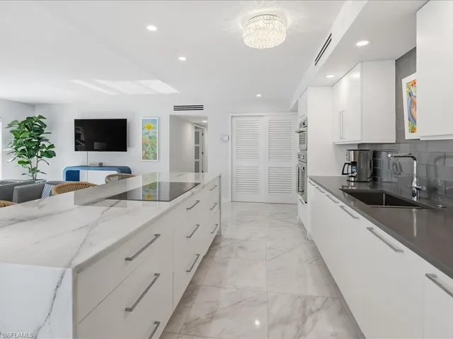 Kitchen featuring modern cabinets, white cabinetry, tasteful backsplash, dark stone countertops, and recessed lighting