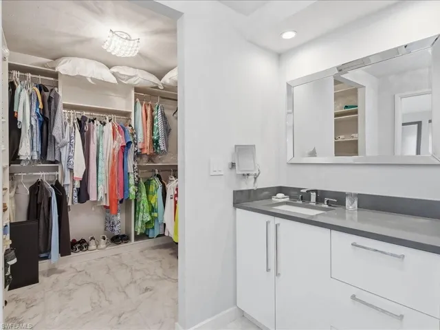 Bathroom featuring a spacious closet, vanity, and light marble finish floors