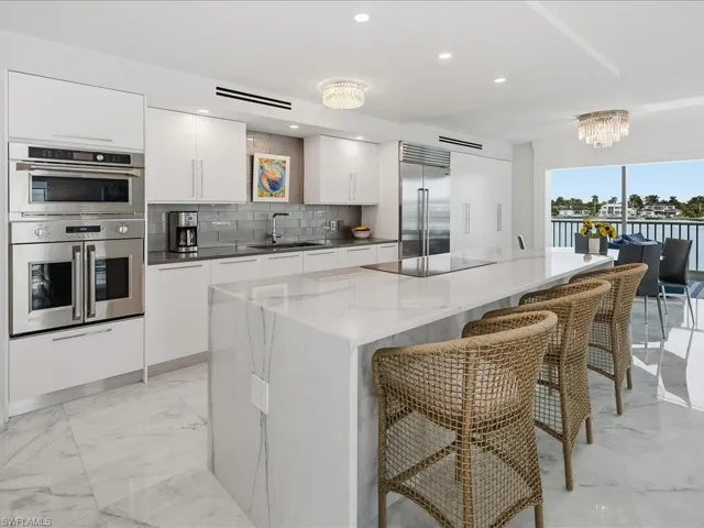 Kitchen with a chandelier, white cabinetry, modern cabinets, stainless steel appliances, and a center island