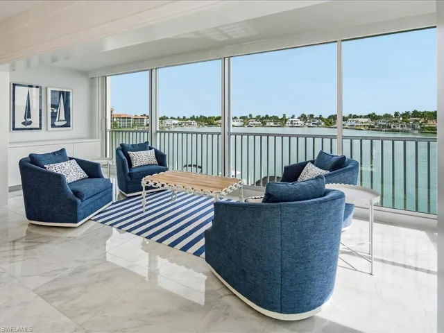 Sunroom featuring a water view, marble tiled floors, and wainscoting