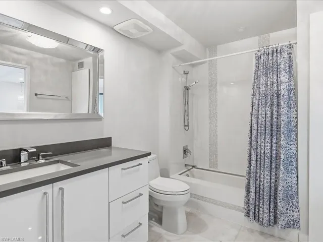 Bathroom featuring shower / bathtub combination with curtain, vanity, and recessed lighting