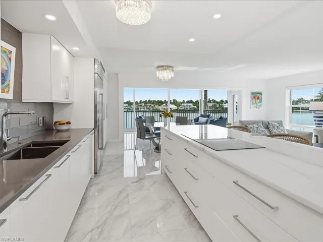 Kitchen with white cabinetry, a water view, a chandelier, decorative backsplash, and dark stone counters