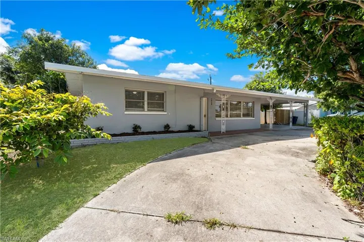Ranch-style home featuring concrete driveway, stucco siding, and an attached carport
