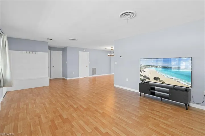 Unfurnished living room featuring light wood-style flooring and a chandelier
