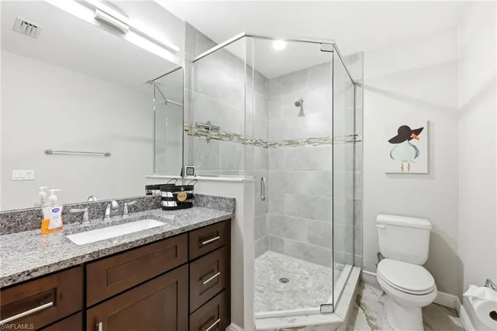 Walk-in shower with clear glass enclosure and light-toned tile surround