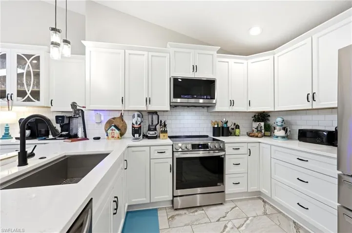 Contemporary kitchen featuring white shaker cabinetry, stainless steel appliances, a subway tile backsplash, and light-toned countertops