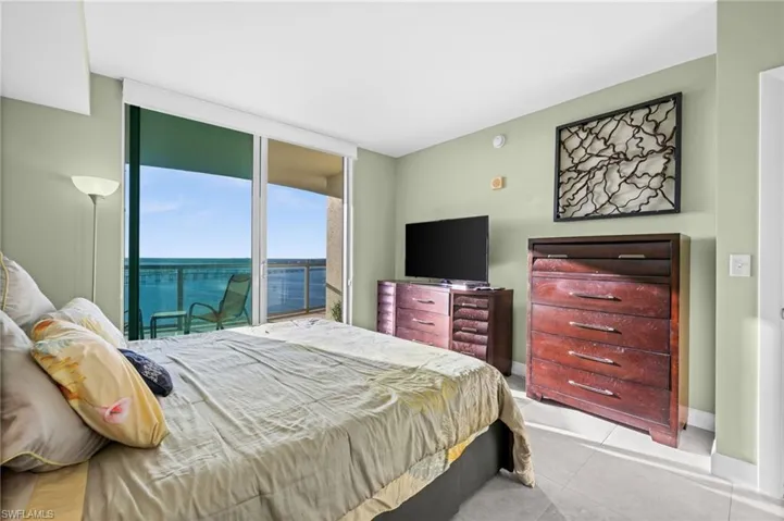 Tiled bedroom featuring access to outside and a wall of windows