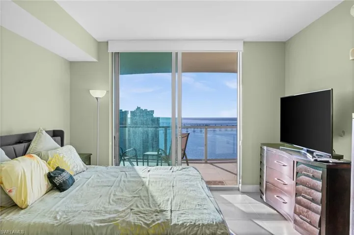 Bedroom with a wall of windows, light tile patterned flooring, and access to outside
