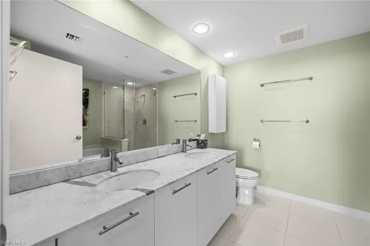Full bath with a stall shower, double vanity, light tile patterned floors, and a bathtub