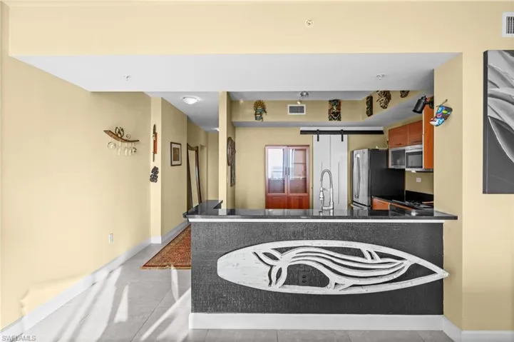 Kitchen with dark countertops, a peninsula, light tile patterned flooring, and black range with electric stovetop