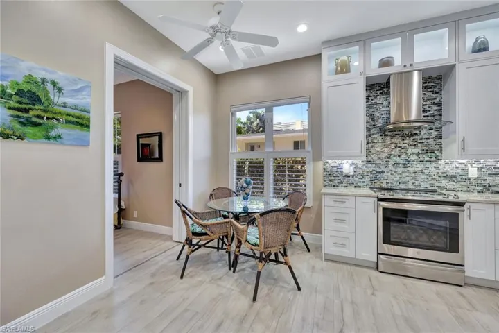 Kitchen featuring stainless steel appliances exhaust hood, custom white cabinets, and decorative backsplash