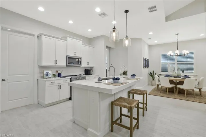 Kitchen featuring pendant lighting, a kitchen breakfast bar, white cabinets, a kitchen island with sink, and recessed lighting