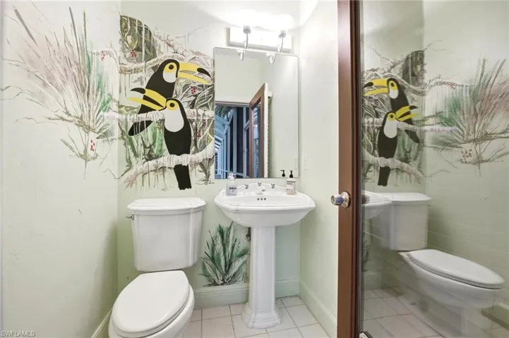 Pedestal sink with dual-handle faucet, wall-mounted mirror, and overhead vanity lighting