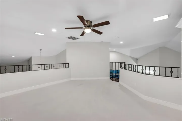 Built in shelves with white carpet and ceiling fan.