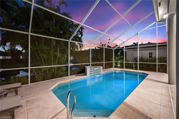 Screened pool enclosure with a geometric pool, integrated water feature, and light-toned tile decking