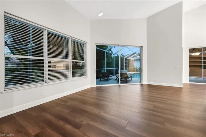 Volume ceiling, recessed lighting, wood-finish flooring, built-in wall niches with integrated lighting, and sliding glass doors