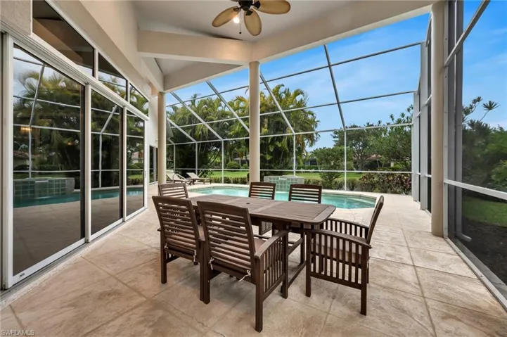 Screened lanai with a textured tile floor, vaulted ceiling, and built-in ceiling fan