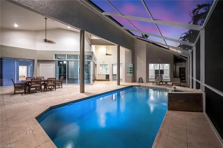 Screened-in pool deck featuring a swimming pool, integrated spa, and expansive patio area