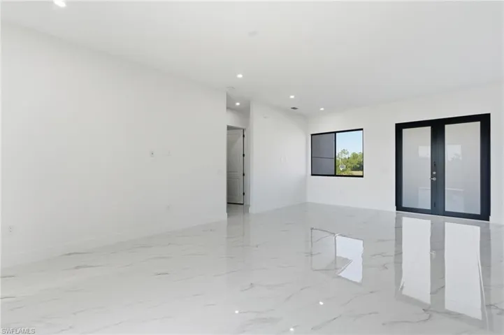 Empty room with french doors, light marble finish floors, and recessed lighting