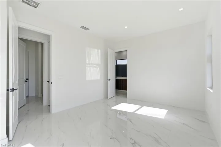 Unfurnished bedroom with light marble finish floors