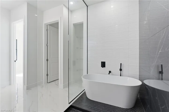 Full bathroom with a freestanding tub, marble tiled flooring, tile walls, and a marble finish shower