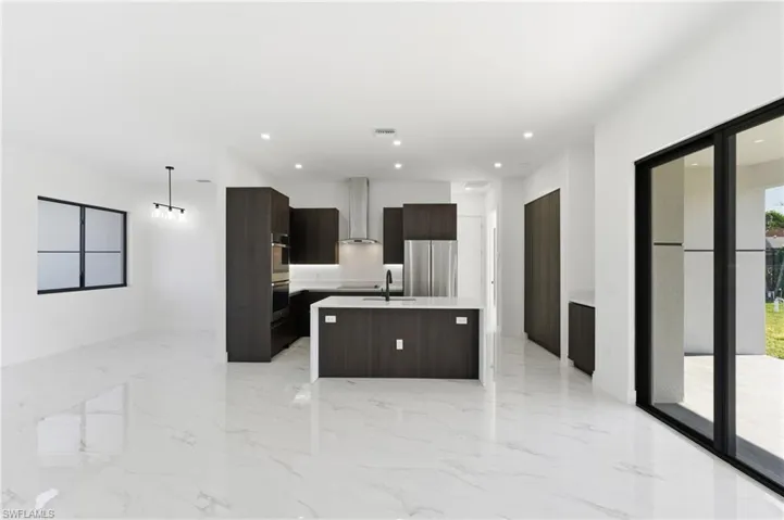 Kitchen with modern cabinets, a kitchen island with sink, dark brown cabinets, open floor plan, and recessed lighting