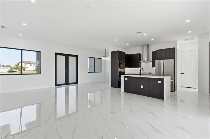 Kitchen with an island with sink, modern cabinets, open floor plan, recessed lighting, and stainless steel appliances