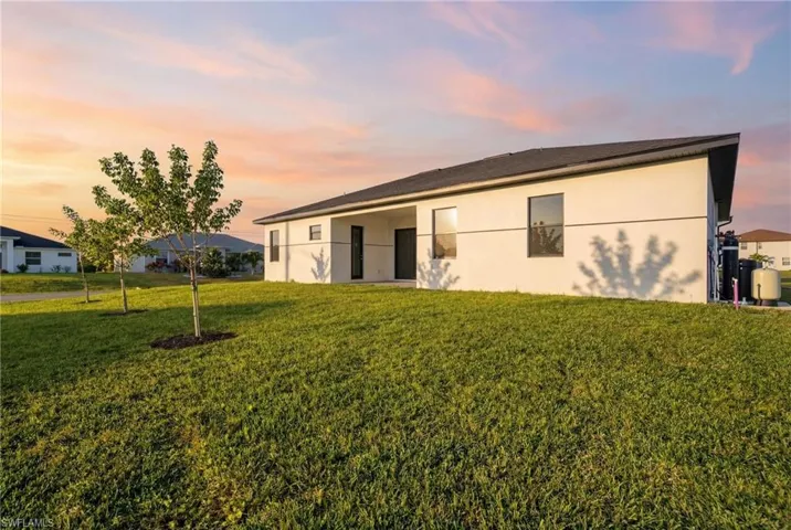 Rear view of house with a patio area, stucco siding, and a yard