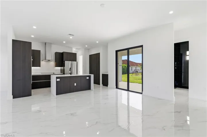 Kitchen featuring modern cabinets, a kitchen island, wall chimney exhaust hood, freestanding refrigerator, and dark brown cabinets