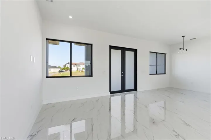 Unfurnished room with french doors, light marble finish flooring, recessed lighting, and a chandelier