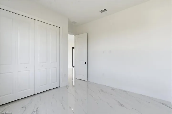 Unfurnished bedroom with light marble finish floors and a closet
