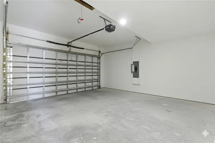 Garage featuring electric panel and a garage door opener