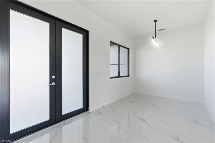 Spare room featuring light marble finish flooring and french doors