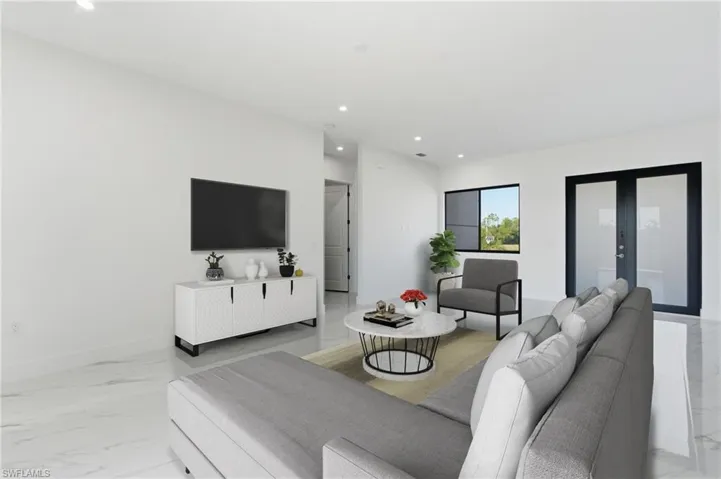 Living room featuring light marble finish flooring, french doors, and recessed lighting