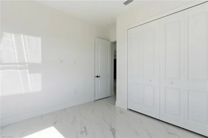 Unfurnished bedroom featuring light marble finish flooring and a closet