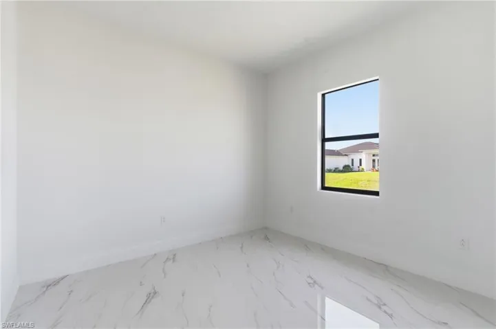 Empty room featuring light marble finish flooring and baseboards