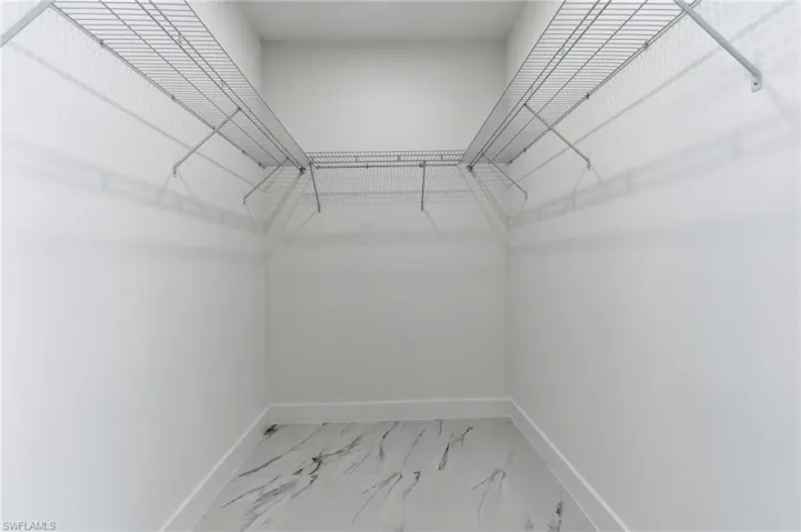 Walk in closet featuring light marble finish floors
