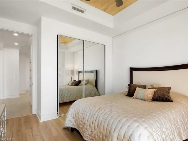 Bedroom with light wood-style flooring, crown molding, recessed lighting, a closet, and a raised ceiling