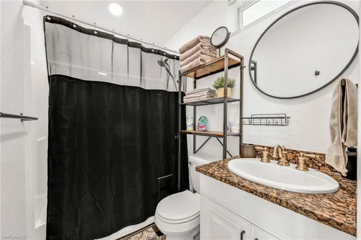 Full bathroom with curtained shower, a textured wall, and vanity