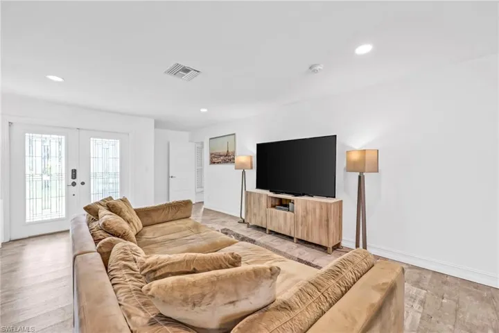 Living room featuring light wood-style flooring, recessed lighting, and french doors