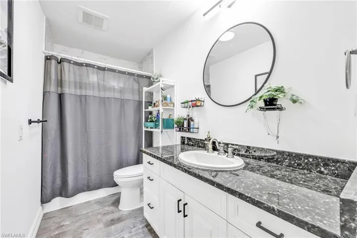 Full bath with vanity, light wood-style floors, and shower / bath combination with curtain