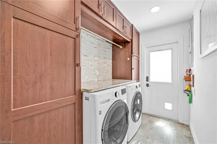 Laundry area featuring light wood-style floors, washing machine and dryer, cabinet space, and recessed lighting
