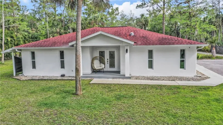 View of front of house with stucco siding, a porch, a front lawn, and a shingled roof