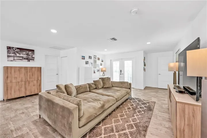 Living room with light wood finished floors, french doors, and recessed lighting