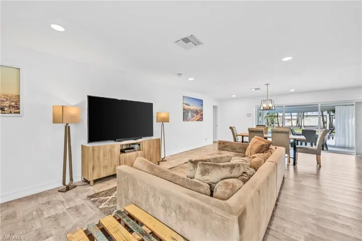 Living area with light wood-type flooring and suspended lighting