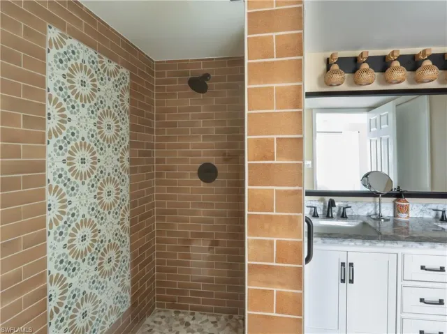 Walk-in shower with unique patterned tile accent, brown subway tile, and dark bronze fixtures