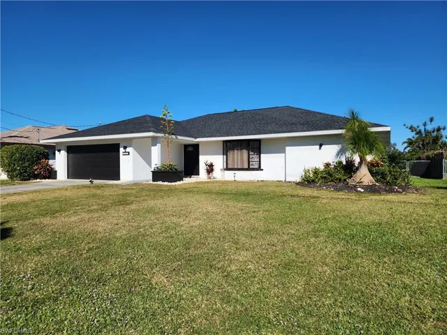 Single story home with a garage and a front lawn
