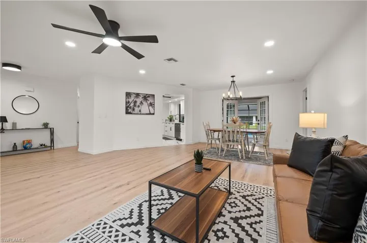 Living room featuring ceiling fan with notable chandelier and light hardwood / wood-style flooring